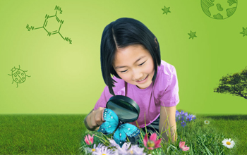 Girl on the green grass looking at a blue butterfly with a magnifying glass